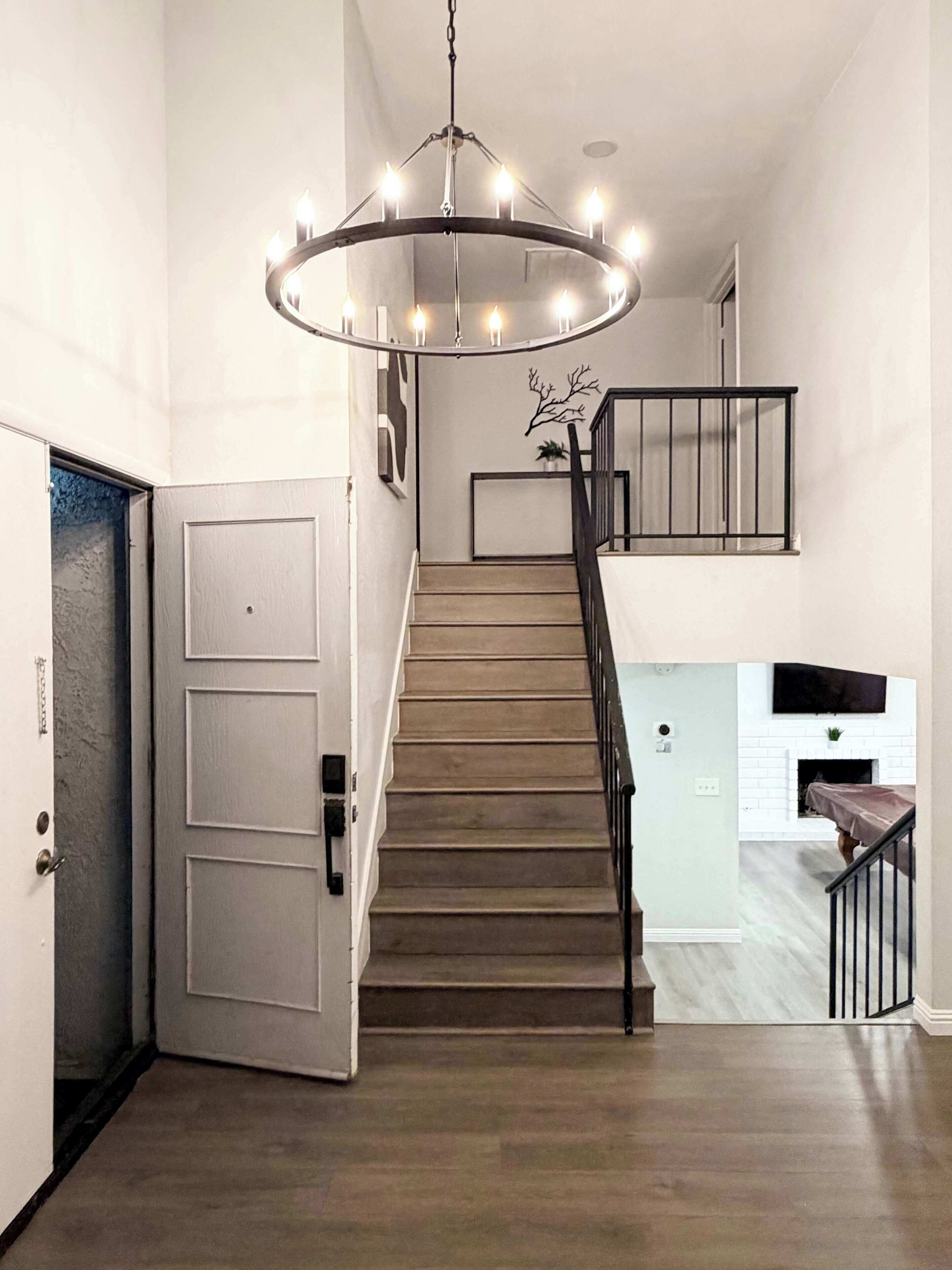 A staircase with a modern design, a chandelier, and a white brick fireplace.