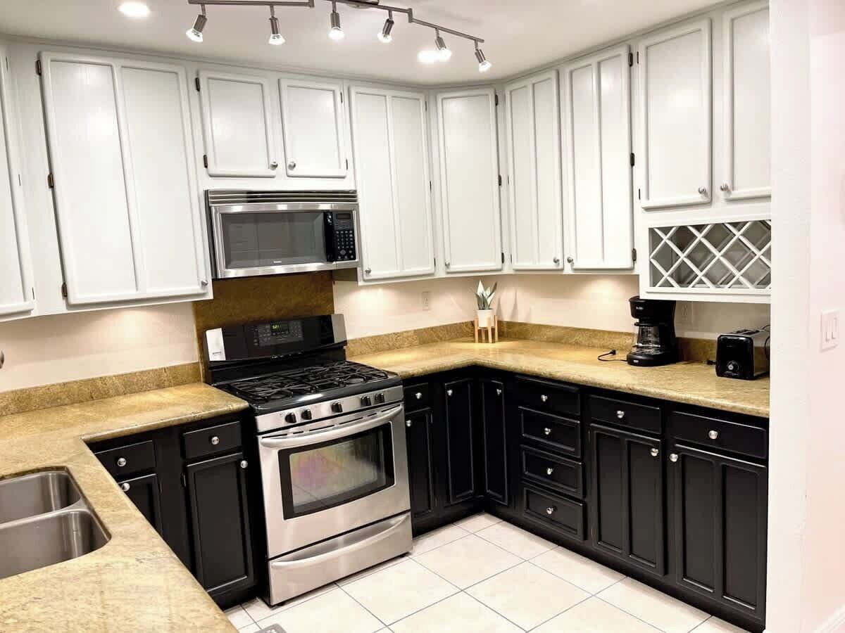 A kitchen with white cabinets, a stainless steel stove, and a microwave.