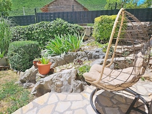 A garden patio with a hanging chair, potted plants, and a stone wall. - Vacation home Smile by Interhome (Imotski)