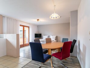 Moderni hotellihuone, jossa on ruokailutila, televisio ja parveke.