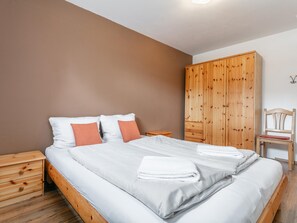 A bedroom with a bed, wooden nightstands, a wardrobe, and a chair.