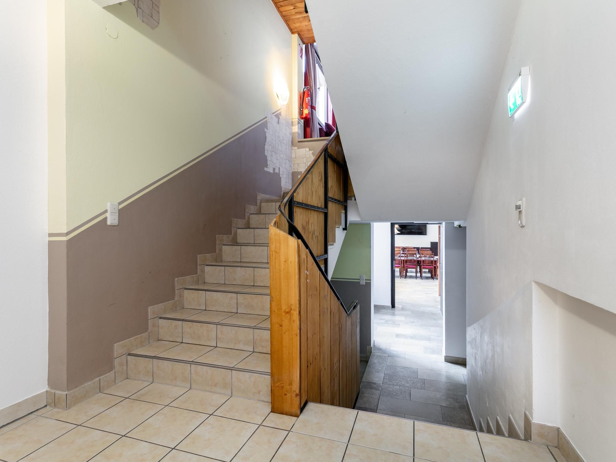 A staircase with wooden steps and a metal handrail, leading to an upper floor.