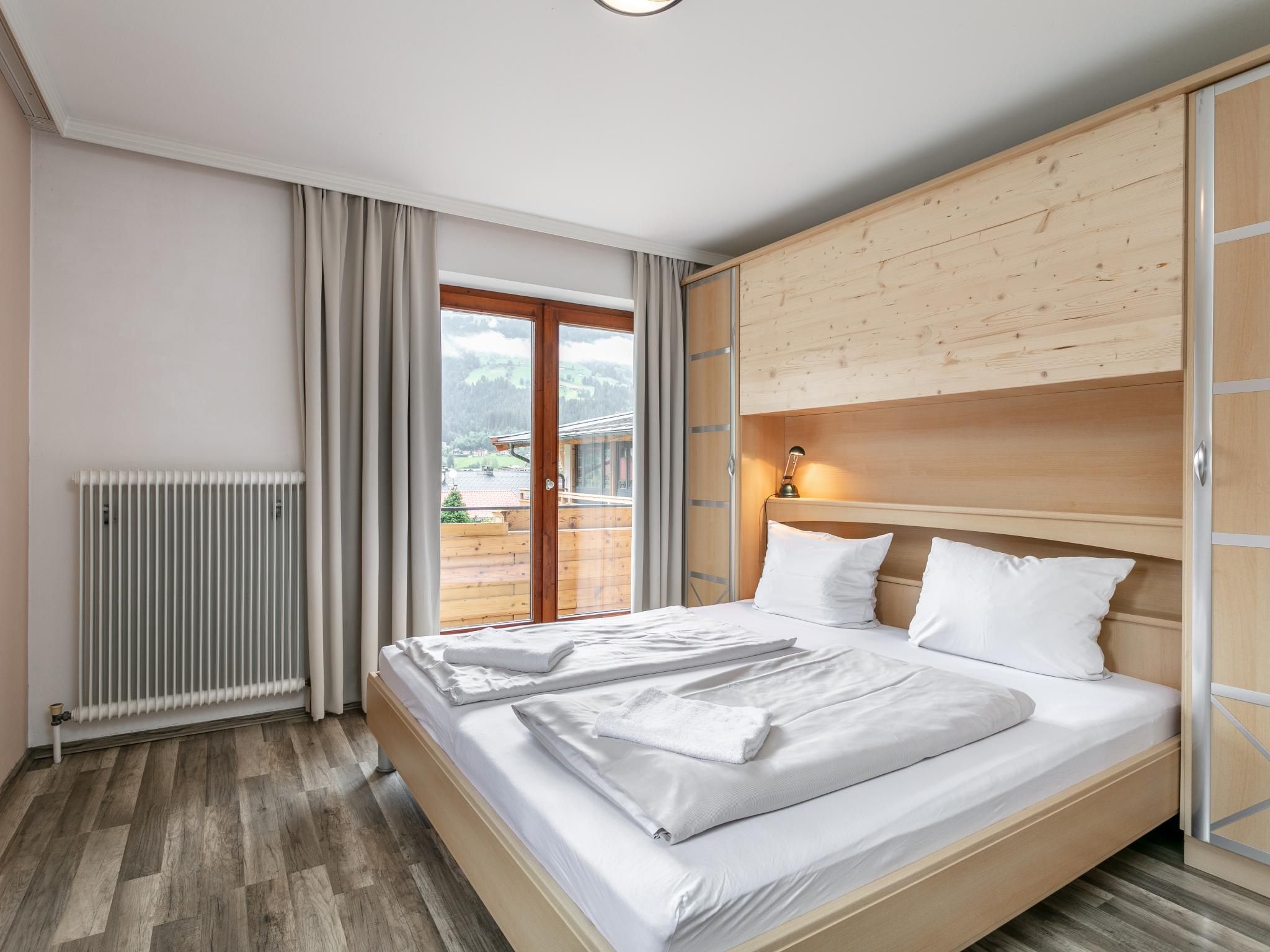 A hotel room with a bed, a radiator, a wooden headboard, and a view of the outdoors.