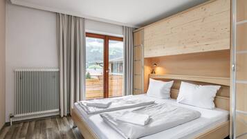 A hotel room with a bed, a radiator, a wooden headboard, and a view of the outdoors.