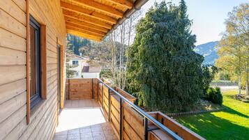 A wooden balcony with a view of a green landscape and trees.
