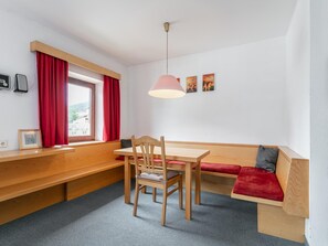 Una habitació amb una banca de fusta, una taula, una cadira, un sofà vermell i una làmpada penjant.