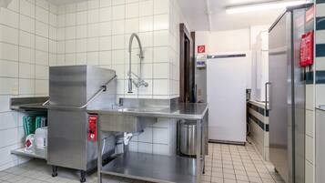 Une cuisine professionnelle équipée d’appareils en acier inoxydable, d’une fontaine à eau et d’une poubelle.