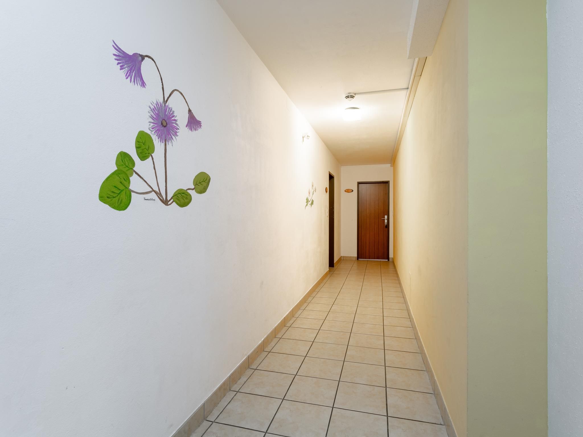 A hallway with a tiled floor and a wall with a floral mural.