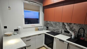 Una cocina moderna con ventana, armarios blancos, un taburete de madera y suelo con motivo de espiga.