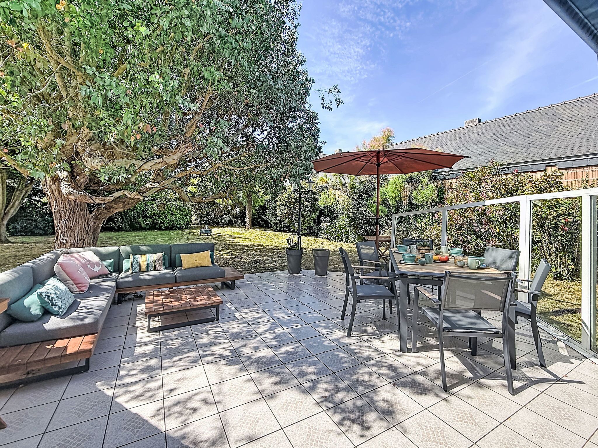 Une terrasse extérieure avec un canapé, des chaises, une table et un parasol.