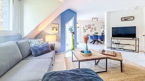 Een moderne woonkamer met een bank, salontafel, televisie en een eethoek.
