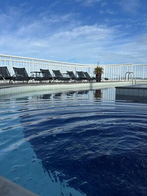 Ein Swimmingpool mit Liegestühlen und einer Brüstung.