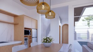 Eine moderne Küche mit Holzausstattung, einer eingebauten Mikrowelle und einem Essbereich mit Holztisch und weißen Stühlen.