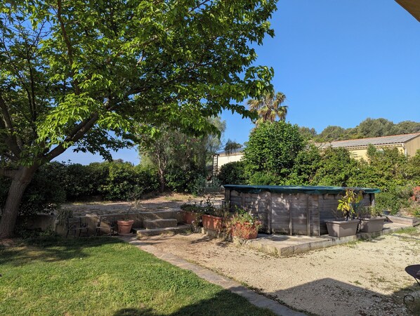 Un jardin agrémenté d’une structure en bois, d’une pelouse et d’un ciel d’un bleu limpide.