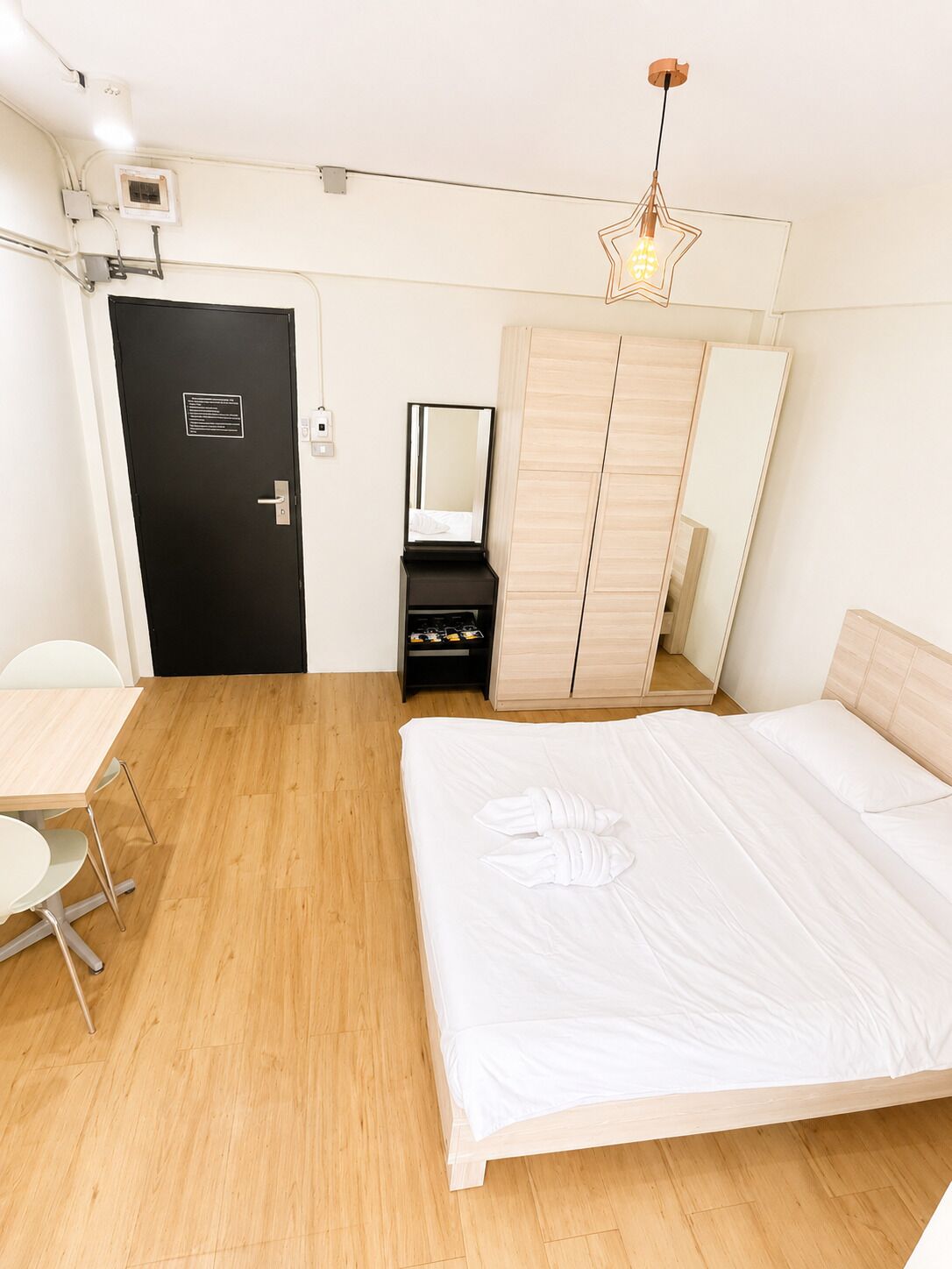 A hotel room with a bed, a desk, a wardrobe, and a mirror.