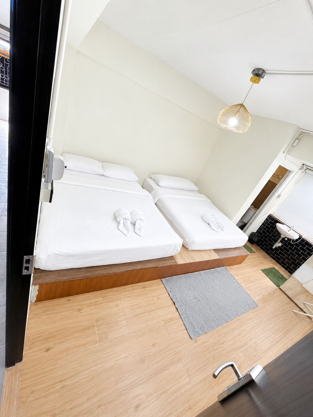 A compact room with two beds, a small sink, and a ceiling light fixture.