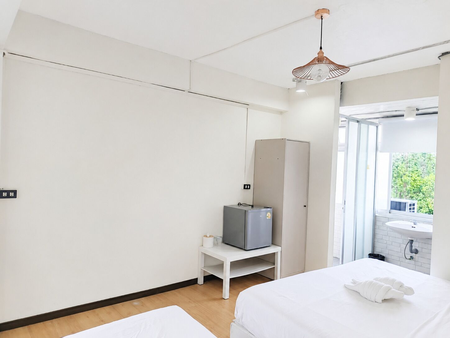 A hotel room with a bed, a television on a stand, a wardrobe, and a bathroom visible through an open door.
