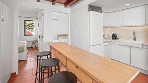 Een moderne keuken met witte kasten, een houten bar en een ingebouwde oven.