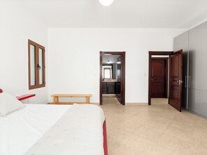 Ein Schlafzimmer mit einem Bett, einem Nachttisch, einer Bank und einem Kleiderschrank.