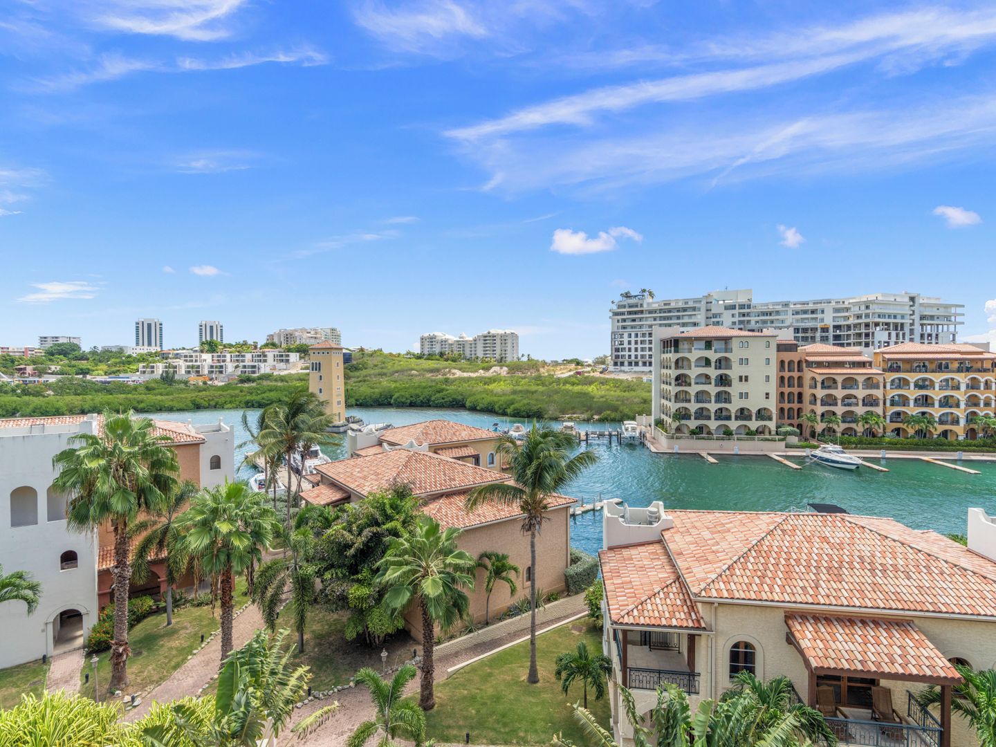 A coastal hotel with a view of the sea, a marina, and surrounding buildings.