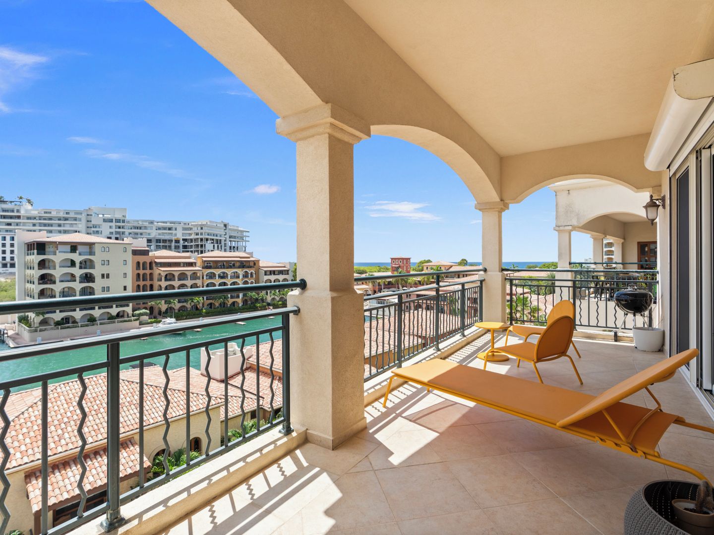 A balcony with a view of a marina and buildings, featuring a table and chairs.