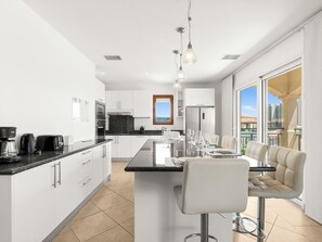 Una cocina moderna con una isla central, taburetes de bar y vistas a la ciudad.