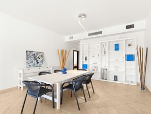 Ein stilvoller Essbereich mit einem weißen Tisch, schwarzen Stühlen und einem weißen Schrank mit Regalen.