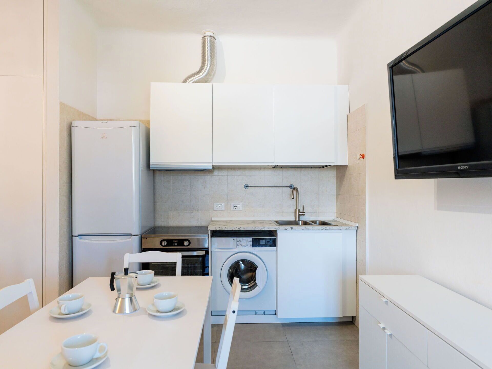 A compact kitchen with a washing machine, a stove, and a sink.