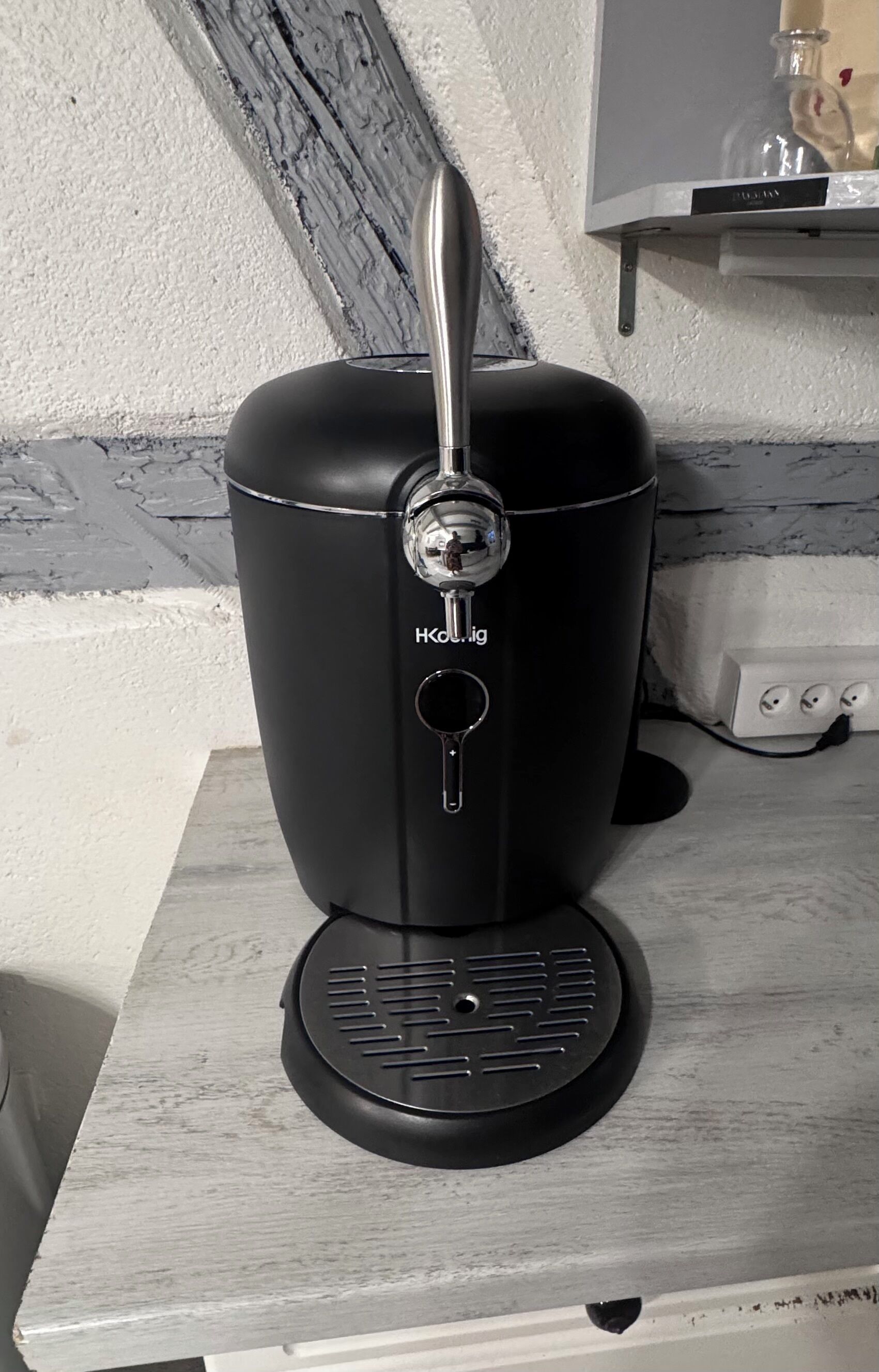 Musta kahvinkeitin, jossa on avainreikä ja metallinen kahva, valkoisella työtasolla.