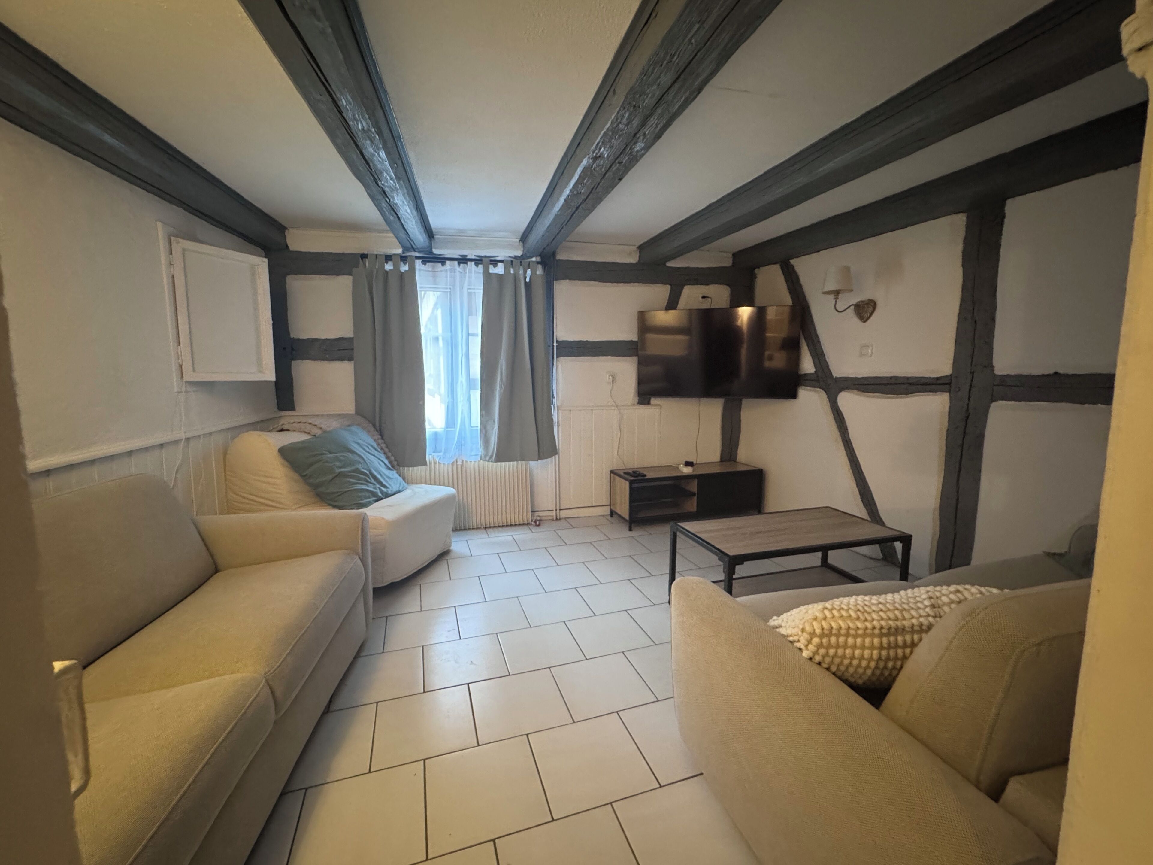 A living room with a sofa, a coffee table, and a TV mounted on the wall.