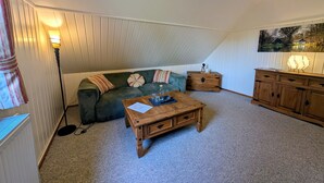 A cozy room with a green sofa, a wooden coffee table, a lamp, a cabinet, and a painting on the wall. - Pension Spreewaldhof Leipe (Lübbenau/Spreewald)