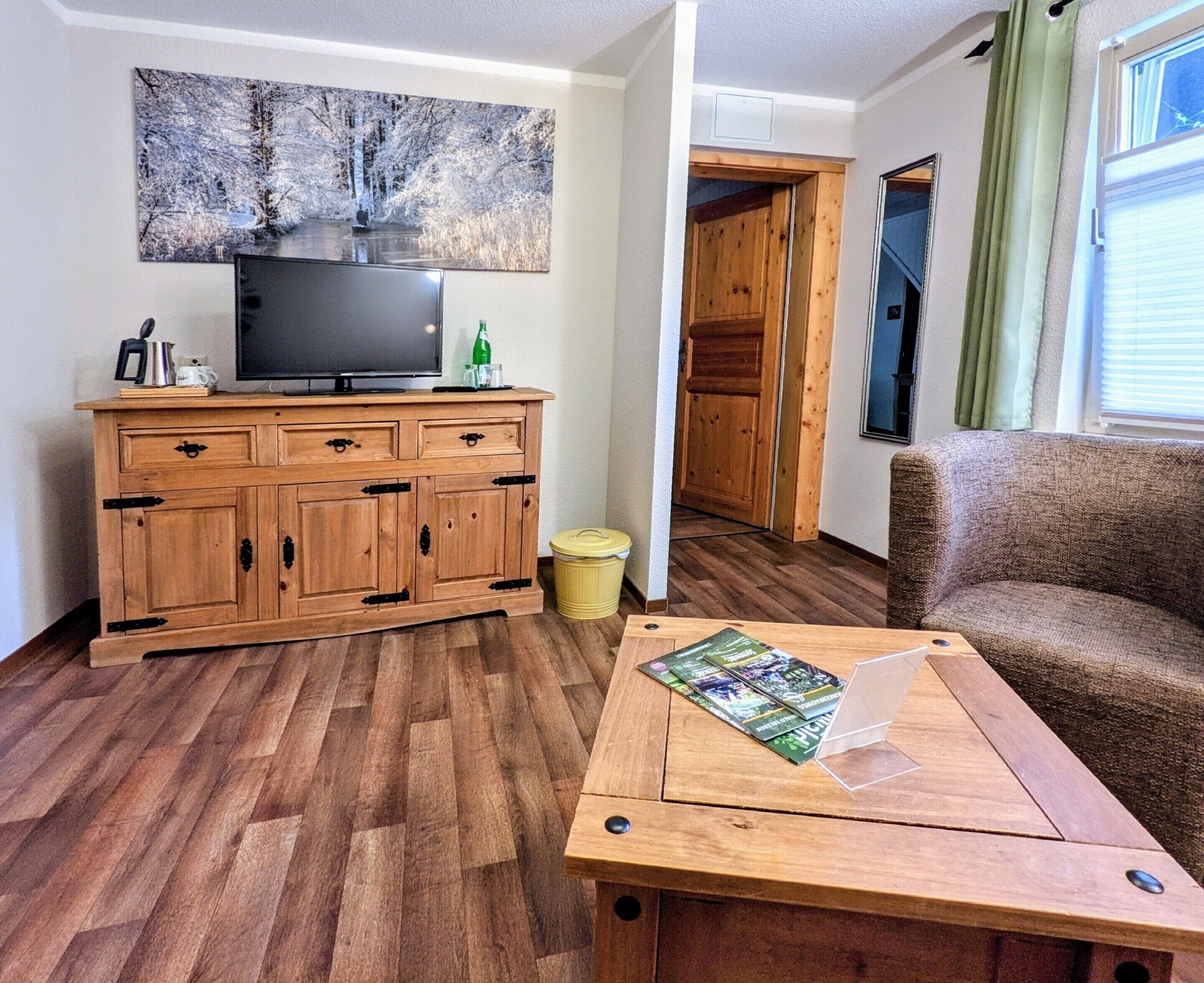 Una sala de estar con un mueble de madera, un televisor, un sofá y una mesa con revistas.