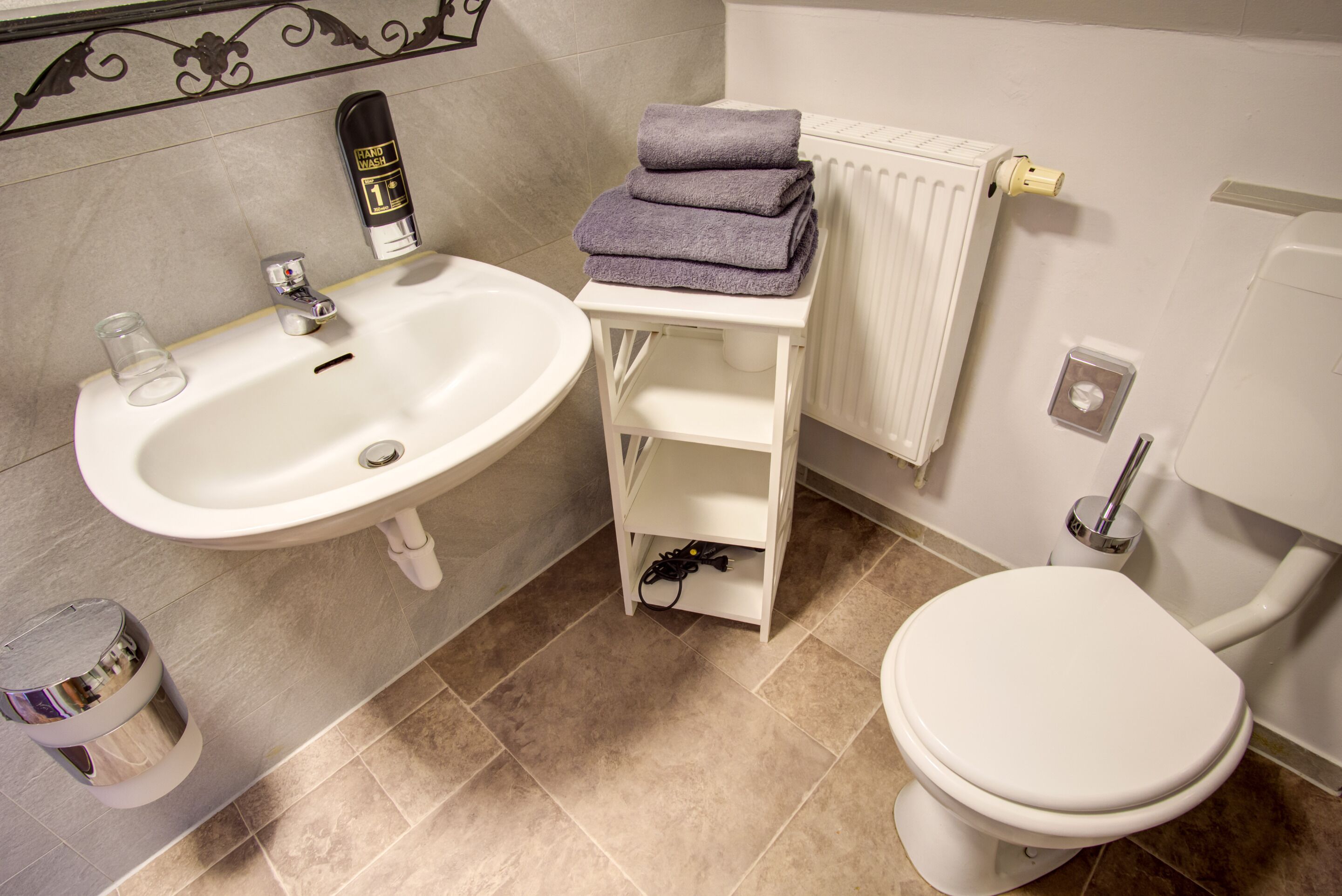 Une salle de bain équipée d’un lavabo, de toilettes et d’un porte-serviettes avec des serviettes pliées.