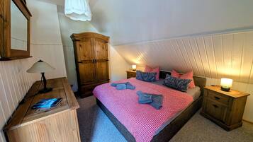 Un dormitorio con cama, armario de madera, mesitas de noche y una lámpara colgante.