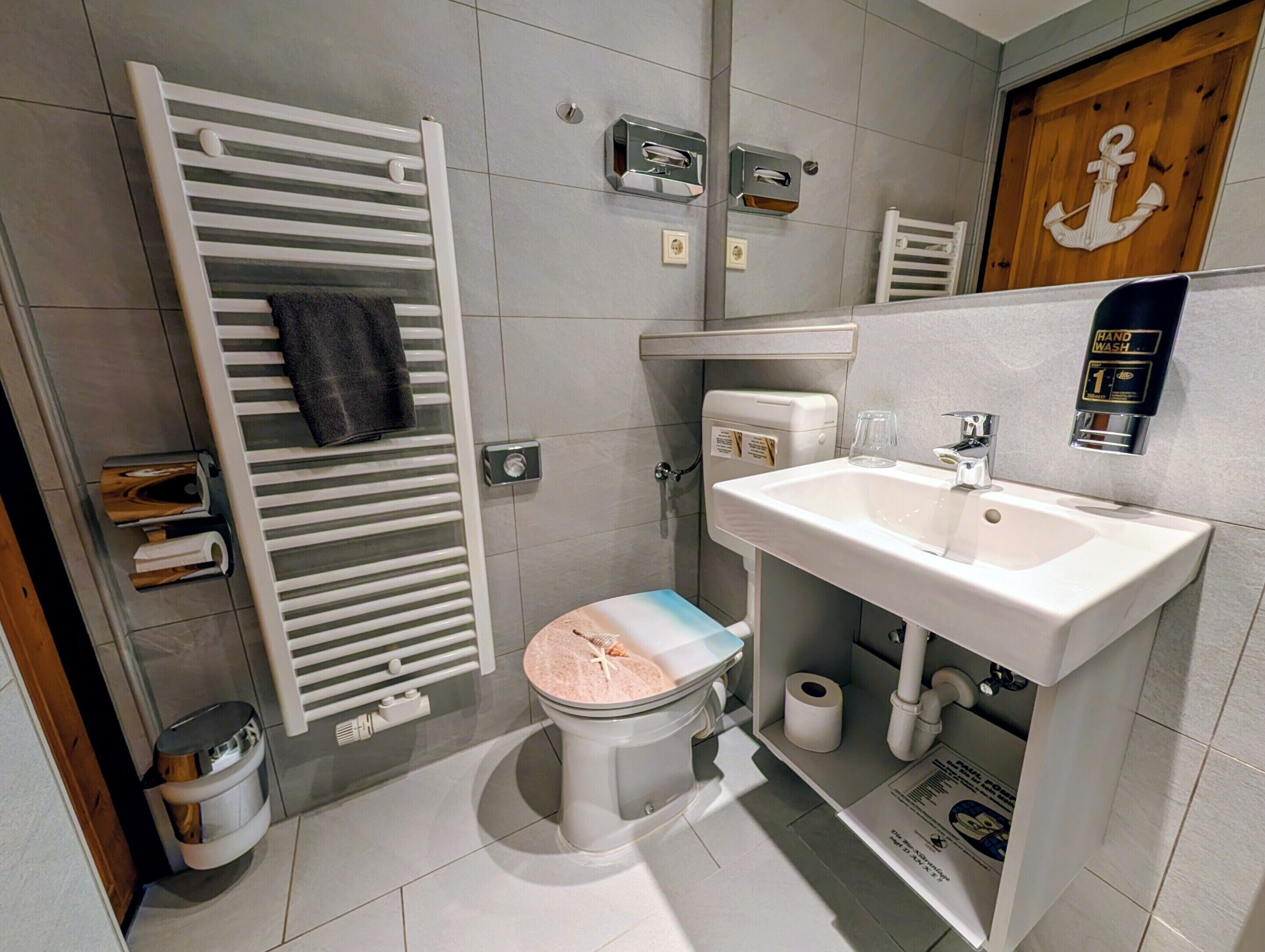 Ein Badezimmer mit Toilette, Bidet, Waschbecken, Handtuchhalter und Spiegel.