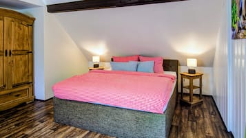 Ein Schlafzimmer mit einem Bett, zwei Nachttischen, einem Holzschrank und einer schrägen Decke.