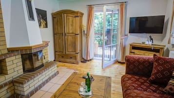 Un salon avec une cheminée, un canapé, un téléviseur et une porte-fenêtre coulissante donnant sur un espace extérieur.