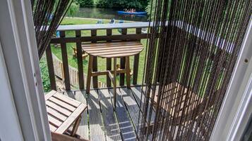 A wooden deck with a view of a river and a boat.