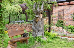 A wooden bench, a stone statue, and a brick wall.