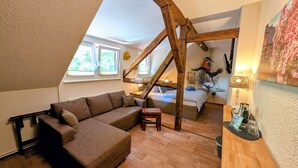 Un dormitorio estilo loft con techo inclinado, un ventanal grande, una cama con cabecera decorativa y una escalera de madera.