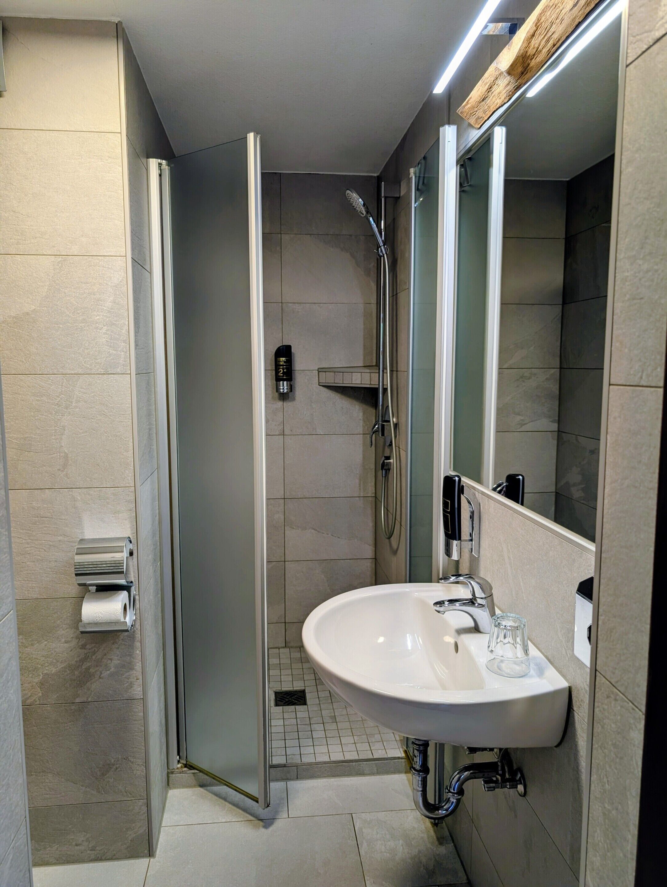 Uma casa de banho moderna com cabine de duche, lavatório e espelho.