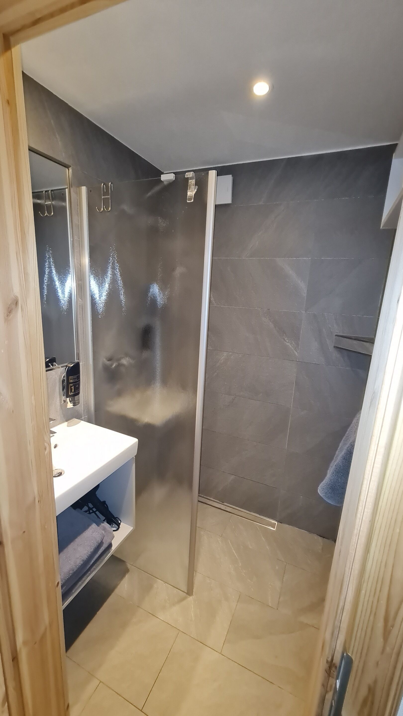 Ein modernes Badezimmer mit einer Duschkabine aus Glas, einem weißen Waschbecken und einem Handtuchhalter.