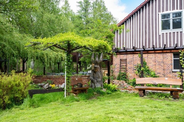 A garden with a wooden bench, a statue, and a pergola.