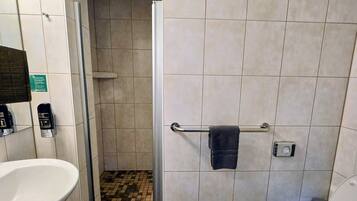 Ein Badezimmer mit weißem Waschbecken, Toilette, Duschbereich und Holzboden.
