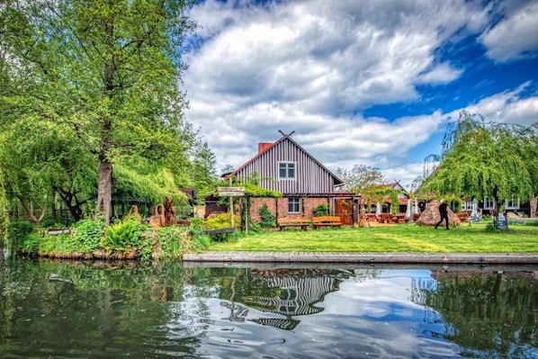A riverside property with a traditional house, a grassy lawn, and a pond reflecting the surroundings.