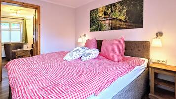 Ein Schlafzimmer mit einem großen Bett, einem Bild an der Wand und einem Fenster mit Vorhängen.