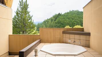 Un jacuzzi en un área de balcón con vista a un paisaje boscoso.