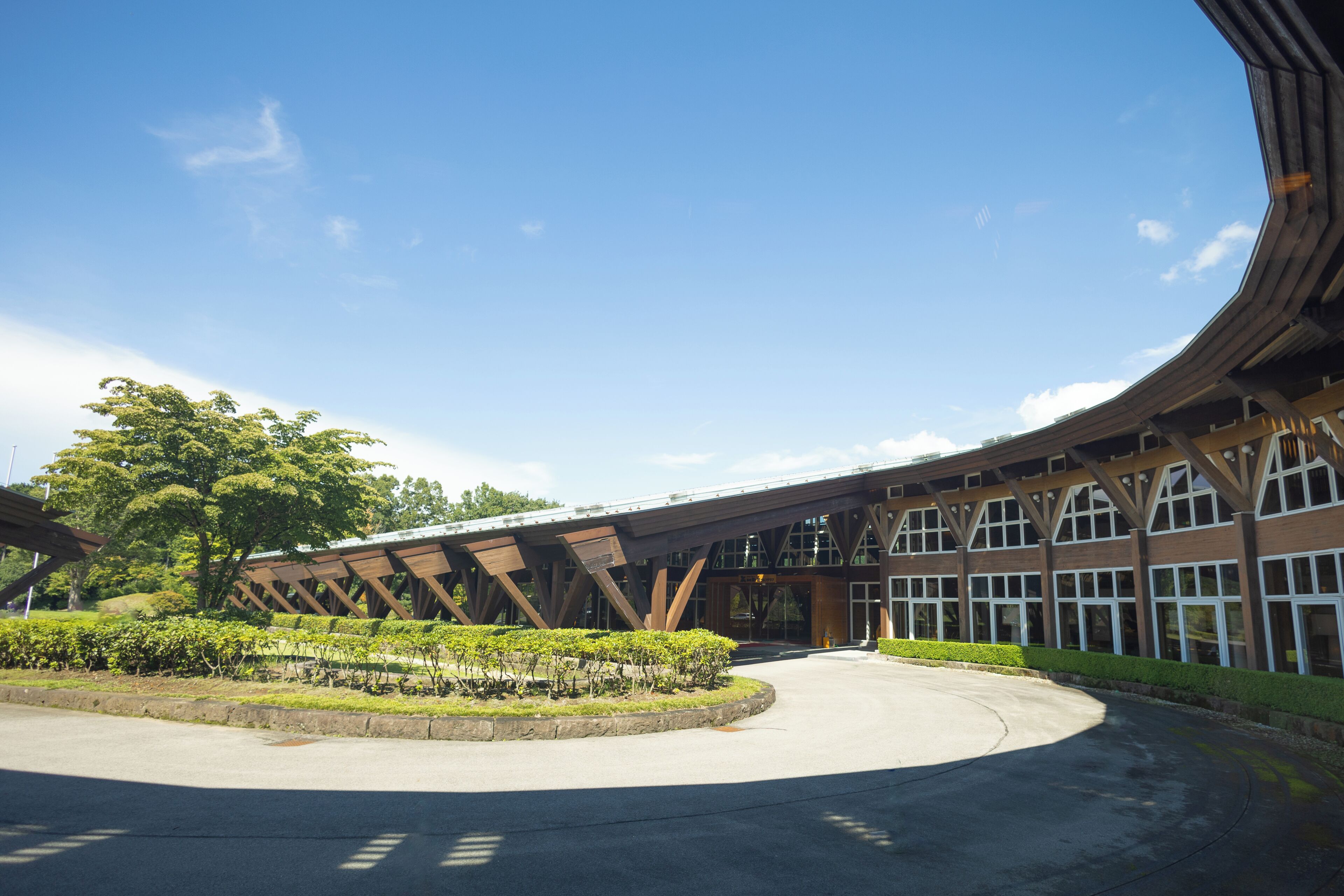 A building with a modern architectural design, featuring a large central courtyard with a circular driveway and surrounding greenery.