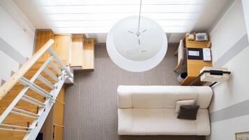 Un interior moderno con un sofá blanco, una escalera de madera y una lámpara en el techo.