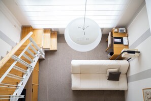 A modern interior with a white sofa, a wooden staircase, and a ceiling light fixture.